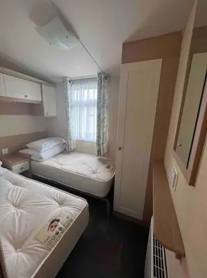 a small room with two beds and a window at Polladras Holiday Park in Helston