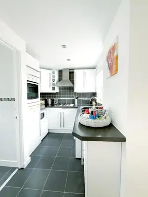 a kitchen with white cabinets and a black counter top at White Eden - explore Cornwall from a comfy central appartment in St Austell