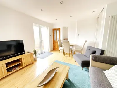 a living room with a tv and a couch and a table at White Eden - explore Cornwall from a comfy central appartment in St Austell