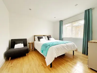a bedroom with a bed and a chair at White Eden - explore Cornwall from a comfy central appartment in St Austell