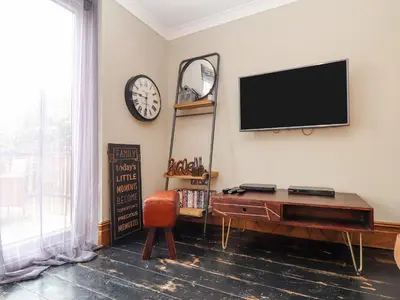 a living room with a tv on the wall and a table at Hillcroft in St Austell