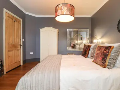 a bedroom with a large white bed and a chandelier at Hillcroft in St Austell