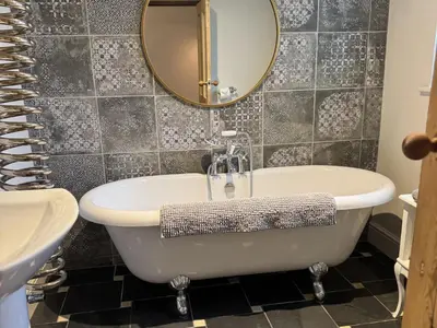a bathroom with a tub and a sink and a mirror at Hillcroft in St Austell