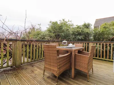 a wicker table and chairs on a wooden deck at Hillcroft in St Austell
