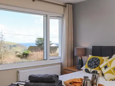 a bedroom with a bed and a large window at Pickney House in Looe