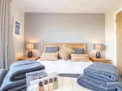 a bedroom with a bed and two chairs at Pickney House in Looe