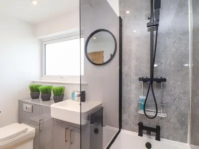 a bathroom with a shower and a sink and a mirror at Pickney House in Looe