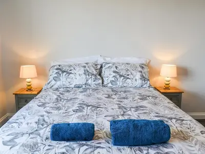 a bed with two blue pillows on it with two lamps at Apartment 15 Harvest Moon in Newquay