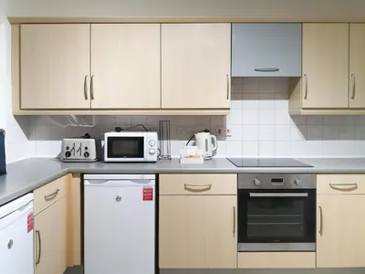 a kitchen with white cabinets and a microwave at Apartment 15 Harvest Moon in Newquay