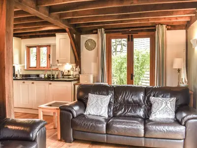 a leather couch in a living room with a kitchen at Chy An Dour in Davidstow