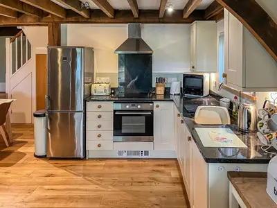 a kitchen with a stainless steel refrigerator and white cabinets at Chy An Dour in Davidstow