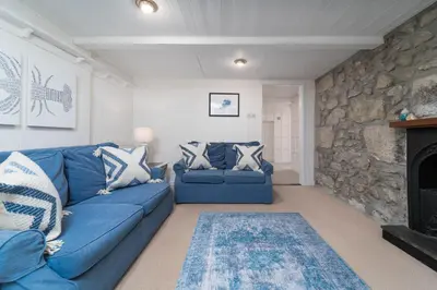 a living room with a blue couch and a stone wall at The Lost Lobster in St Ives