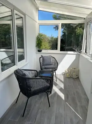 a screened in porch with two chairs and windows at Sunny Corner - lovely 2 bedroom appt in Redruth