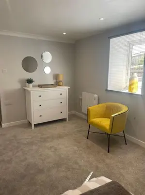 a room with a yellow chair and a dresser at Sunny Corner - lovely 2 bedroom appt in Redruth