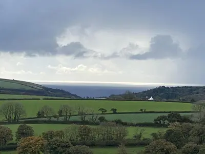 a green field with the ocean in the background at The Pilchard - Lydcott Glamping Cornwall, sea view in East Looe