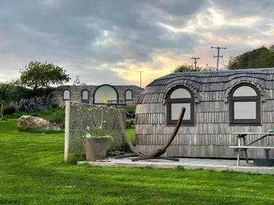 a large building with a hose next to a yard at The Pilchard - Lydcott Glamping Cornwall, sea view in East Looe