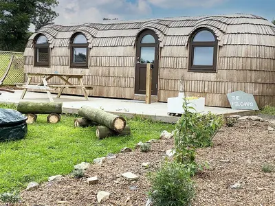 a large wooden building with a sign in front of it at The Pilchard - Lydcott Glamping Cornwall, sea view in East Looe