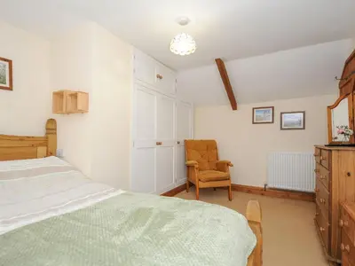 a bedroom with a bed and a chair at Henwood Barn in Liskeard