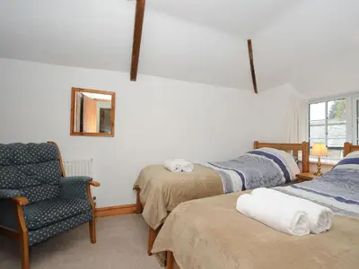 a room with two beds and a chair and a mirror at Small Barn in Liskeard