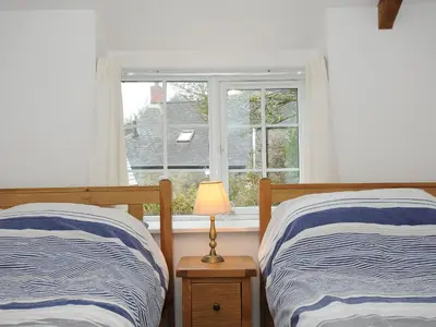 two beds in a bedroom with a window at Small Barn in Liskeard