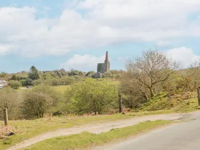 a dirt road with a church in the distance at Small Barn in Liskeard