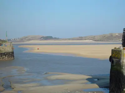 a body of water with a beach and a pier at Mole Cottage in Liskeard