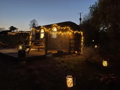 a lit up yurt with lights in a yard at Prosecco - Lydcott Glamping Cornwall, sea views in East Looe