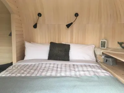 a bedroom with a bed with a wooden wall at Prosecco - Lydcott Glamping Cornwall, sea views in East Looe