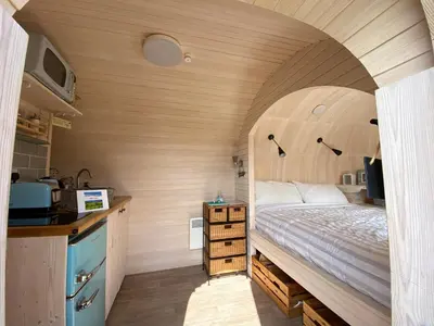 a small bedroom with a bed and a kitchen at Prosecco - Lydcott Glamping Cornwall, sea views in East Looe