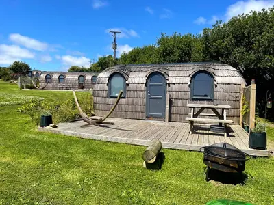 a yurt with a table and a picnic table in the grass at Prosecco - Lydcott Glamping Cornwall, sea views in East Looe