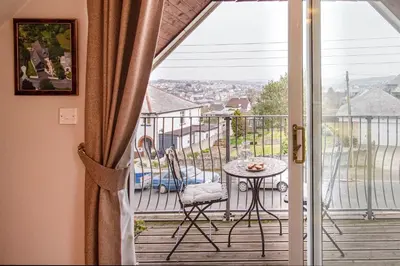 a room with a balcony with a table and a view at Orchard House Wadebridge Self Catering in Wadebridge