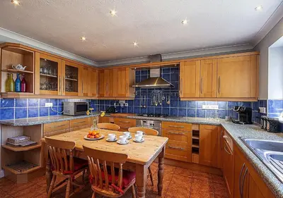 a kitchen with wooden cabinets and a table with chairs at Orchard House Wadebridge Self Catering in Wadebridge