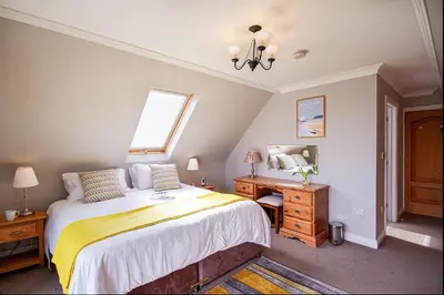 a bedroom with a bed and a desk and a window at Orchard House Wadebridge Self Catering in Wadebridge