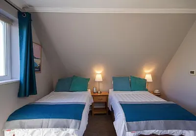 two beds in a small room with blue pillows at Orchard House Wadebridge Self Catering in Wadebridge