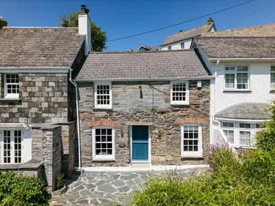 a stone house with white windows and a blue door at Mermaid Cottage in Port Isaac