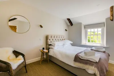a bedroom with a bed and a mirror and a chair at Mermaid Cottage in Port Isaac
