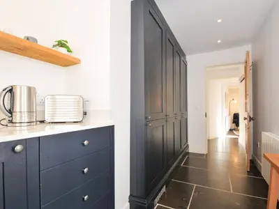 a kitchen with a black cabinet and a hallway at Mermaid Cottage in Port Isaac