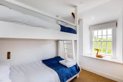 a bedroom with two bunk beds and a window at Mermaid Cottage in Port Isaac