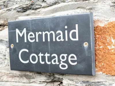 a sign that reads mermaid cottage on a stone wall at Mermaid Cottage in Port Isaac