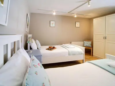 a small bedroom with two beds and a chair at Stone Barn in Camelford