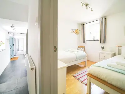 a small bedroom with two beds and a bathroom at Stone Barn in Camelford