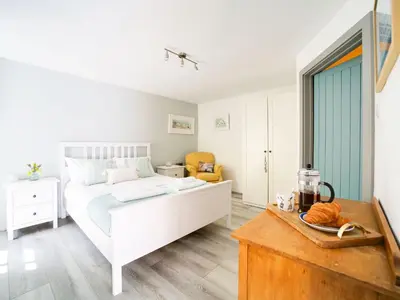 a bedroom with a white bed and a blue door at Stone Barn in Camelford