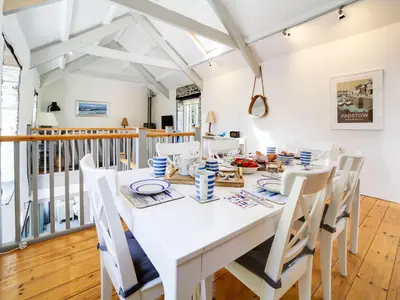 a white dining room with a white table and chairs at Stone Barn in Camelford