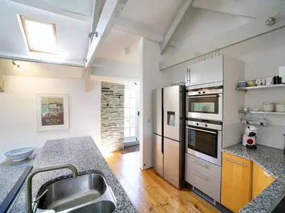 a kitchen with stainless steel appliances and a wooden floor at Stone Barn in Camelford