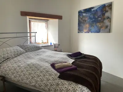 a bedroom with a bed with purple pillows on it at Rosehip Barn in Launceston
