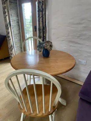 a wooden table with two chairs and a vase on it at Rosehip Barn in Launceston