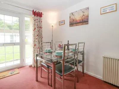 a dining room with a glass table and chairs at Sycamores in Liskeard