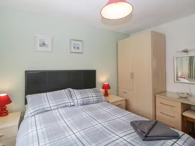 a bedroom with a bed with a black headboard and two lamps at Sycamores in Liskeard