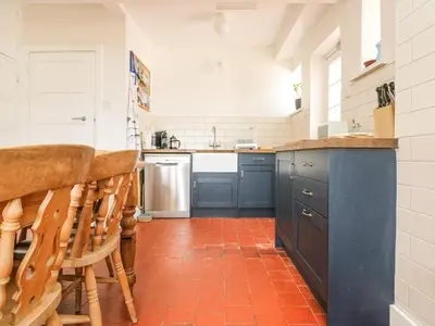 a kitchen with blue cabinets and a red tile floor at Flushing Meadow in Helston