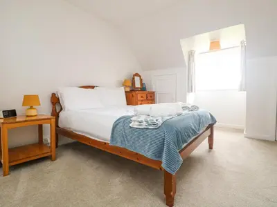 a bedroom with a bed and a table and a window at Flushing Meadow in Helston